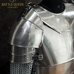 May include: Polished steel armor, featuring articulated shoulder plates and a chest piece. The armor includes chainmail and leather straps. The "Battle Queen Armory" logo is visible in the upper left corner.
