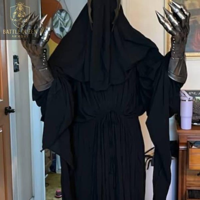 May include: A black hooded robe with metal claw gauntlets. The gauntlets have long, sharp claws and are attached to a leather-like glove. The robe is long and flowing, with a high collar. The Battle Queen Armory logo is visible in the upper left corner.