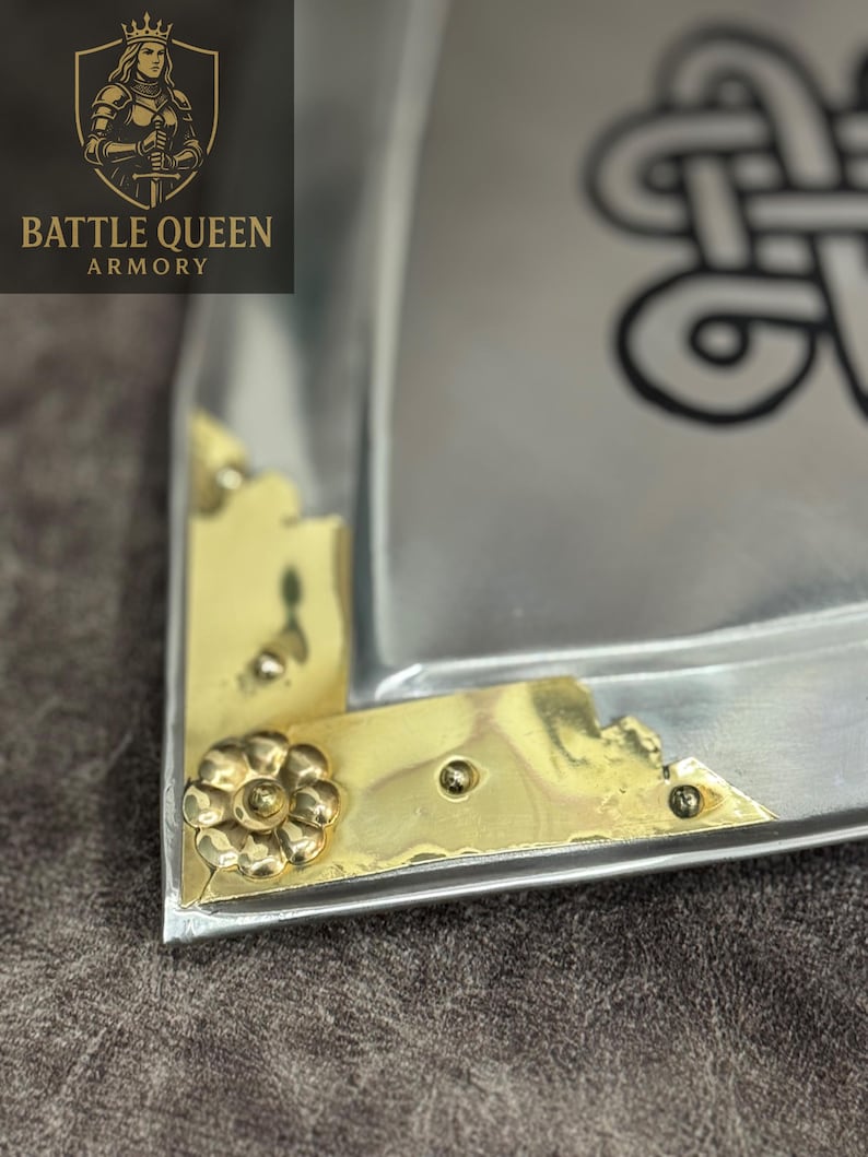 Puede incluir: Primer plano de una bandeja met&aacute;lica con detalles de esquina de lat&oacute;n y un adorno floral. La bandeja tiene un acabado plateado y un dise&ntilde;o de nudo celta. El logotipo "BATTLE QUEEN ARMORY" es visible en la esquina superior izquierda.