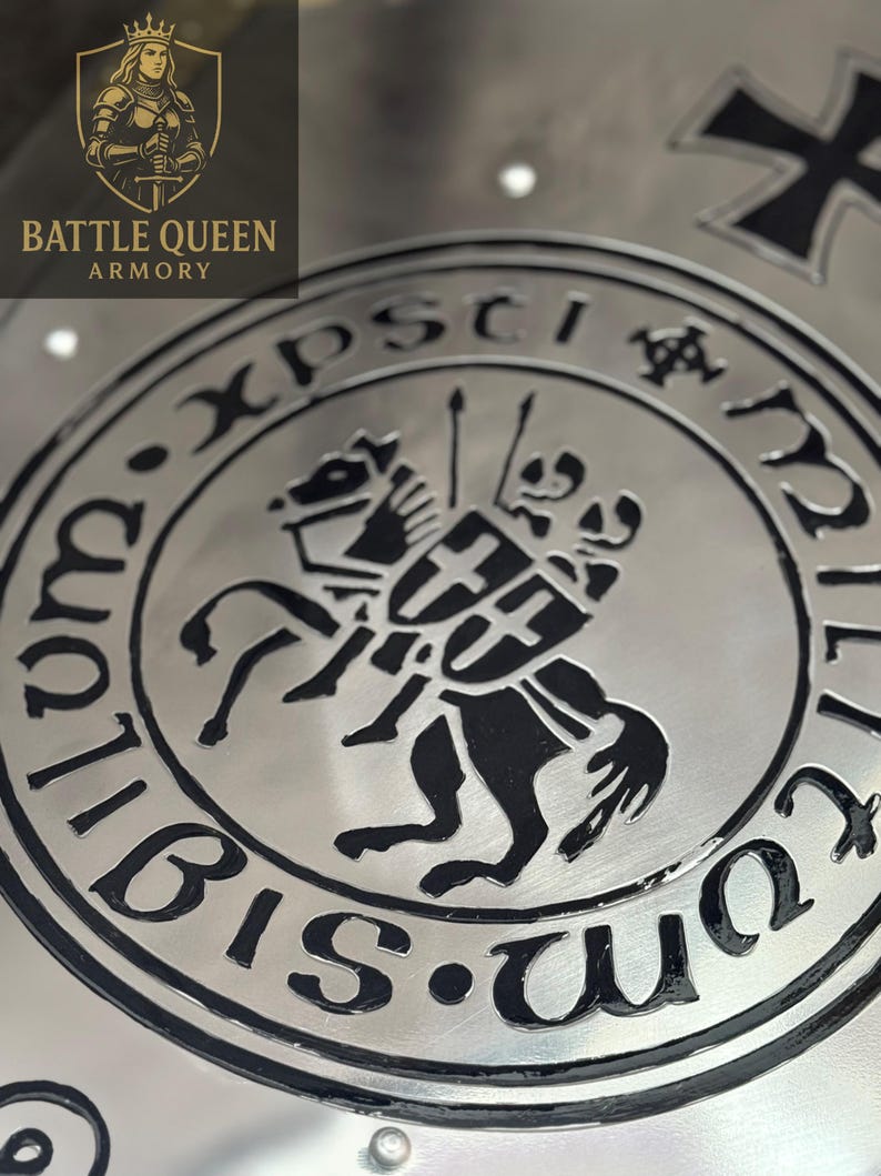 Puede incluir: Primer plano de un escudo de metal plateado con un emblema negro que representa a un caballero a caballo y el texto "Xpsti". El escudo tambi&eacute;n tiene las palabras "Battle Queen Armory" y un logotipo de una reina.