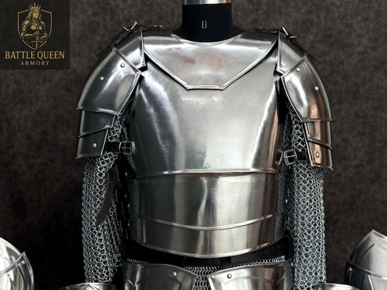 May include: A polished, silver-colored suit of armor, displayed on a mannequin. The armor includes a chest plate, shoulder guards, and chainmail. The logo "BATTLE QUEEN ARMORY" is visible in the upper left corner.