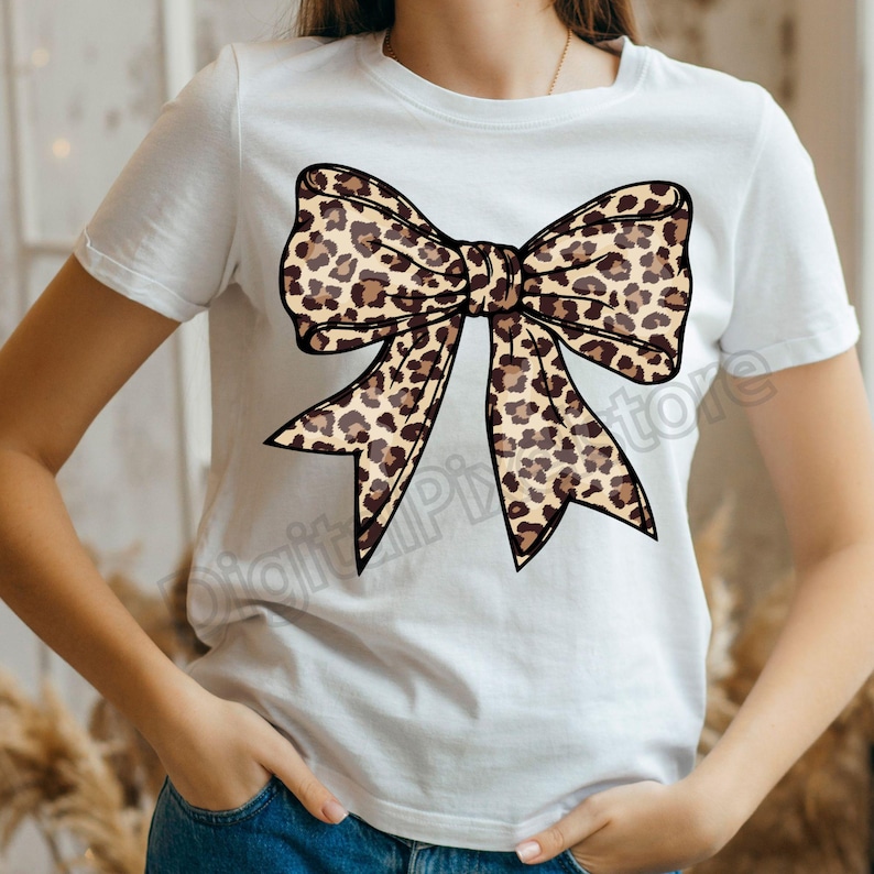 May include: White t-shirt with a large brown and black leopard print bow.