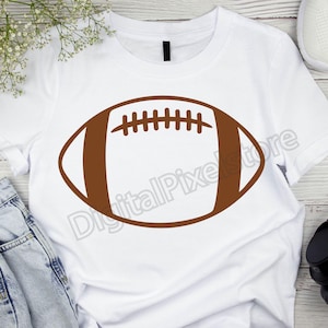 Pode incluir: Uma camiseta branca com um contorno marrom de uma bola de futebol americano.