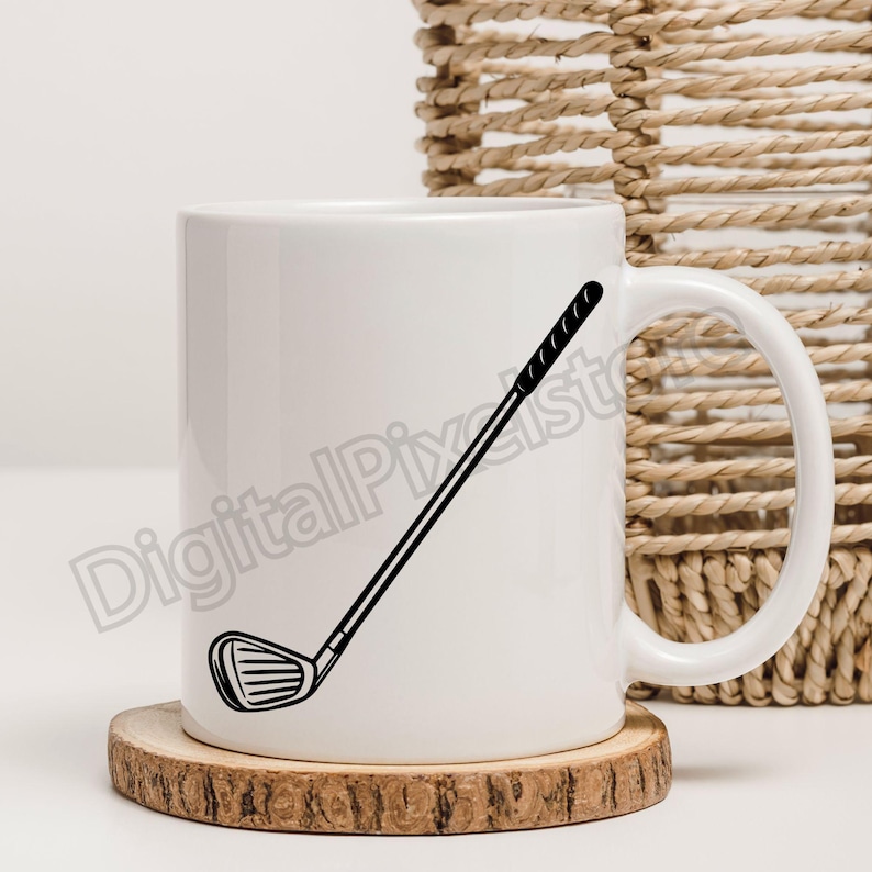 May include: White ceramic mug featuring a black golf club graphic. The mug sits on a round wooden coaster. A woven basket is in the background.