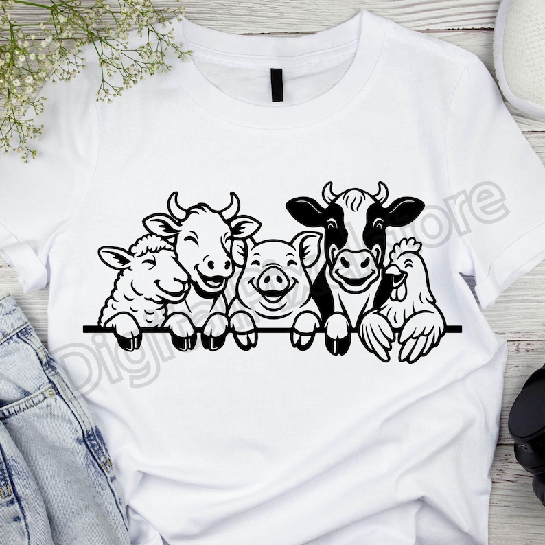 May include: White t-shirt with a black and white graphic of a sheep, cow, pig, cow, and chicken. The farm animals are smiling and appear to be holding onto a black line. The shirt is made of a soft material.