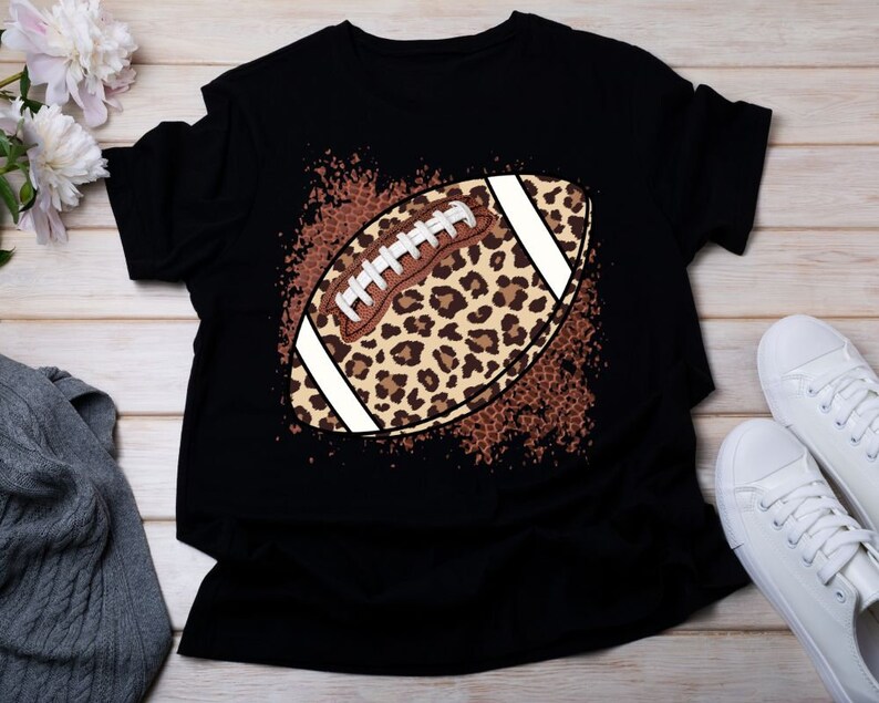Pu&ograve; includere: Maglietta nera con un design a forma di pallone da football con stampa leopardata. Il pallone da football &egrave; bianco con lacci marroni e un motivo leopardato marrone e beige.
