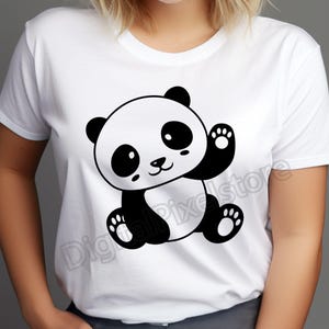 May include: White t-shirt featuring a black and white cartoon panda bear waving. The panda has large eyes and a cute smile.