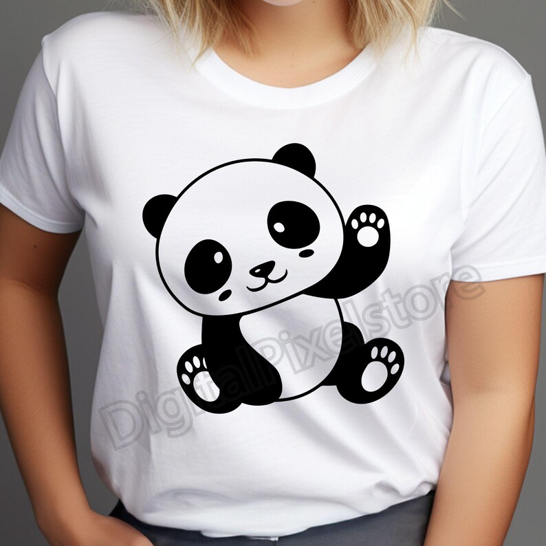 May include: White t-shirt featuring a black and white cartoon panda bear waving. The panda has large eyes and a cute smile.