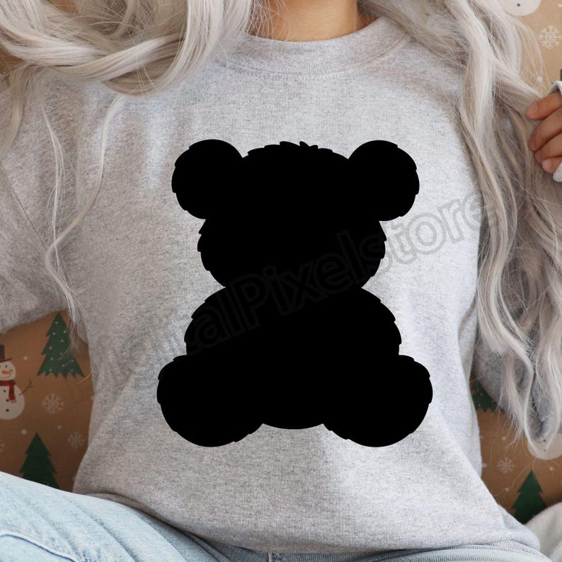 May include: A light gray sweatshirt featuring a large black silhouette of a teddy bear. The bear has rounded ears, a round head, and a fluffy body. The sweatshirt is a neutral color, suitable for various outfits.