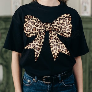 May include: Black t-shirt with a large leopard print bow design.