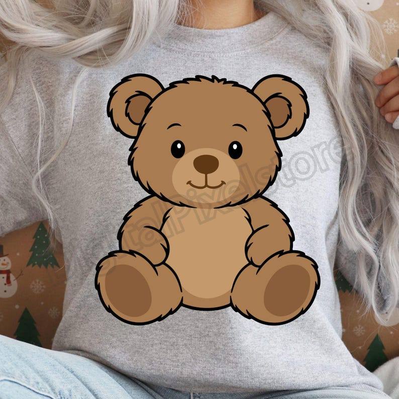 May include: A light gray sweatshirt featuring a cartoon teddy bear illustration. The bear is brown with a black outline, and has a smiling face. The sweatshirt is a casual style, suitable for everyday wear.