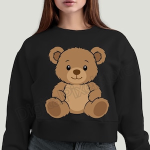 May include: Black crewneck sweatshirt featuring a cartoon teddy bear illustration. The bear is brown with a light brown belly and a dark brown nose and eyes. The bear is sitting with its arms and legs outstretched.