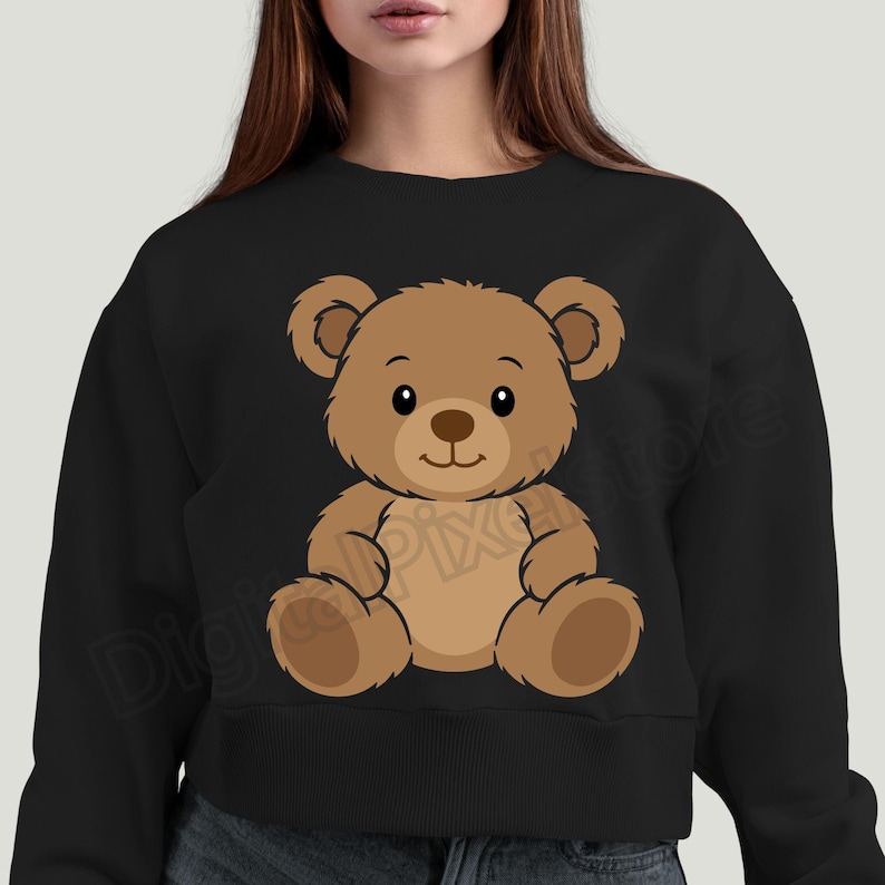 May include: Black crewneck sweatshirt featuring a cartoon teddy bear illustration. The bear is brown with a light brown belly and a dark brown nose and eyes. The bear is sitting with its arms and legs outstretched.