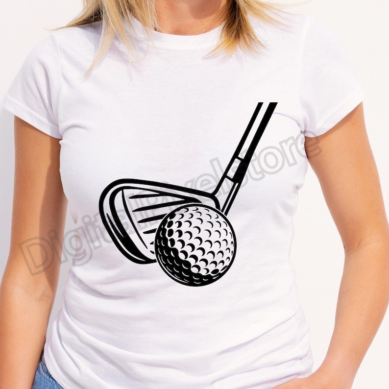 May include: Black and white graphic of a golf club and golf ball. The golf club is positioned above the ball, ready to strike. The ball has a dimpled surface. The design is on a white t-shirt.