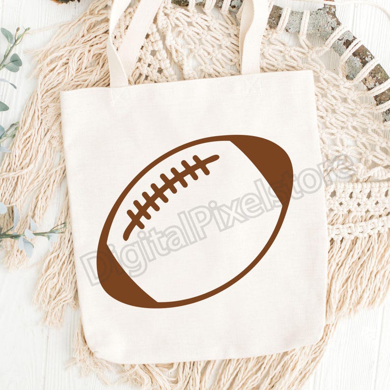 Pode incluir: Uma bolsa de lona branca com um contorno marrom de uma bola de futebol americano.