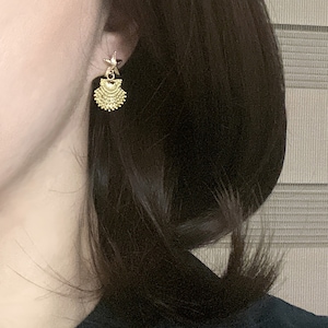 May include: Gold tone earrings with a layered, fan-shaped design. The earrings are dangling and have a delicate, feminine look.