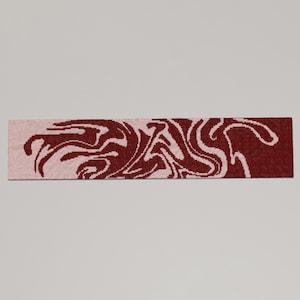 May include: A rectangular scarf with a swirling pattern. The scarf features a color gradient, transitioning from a light pink to a deep burgundy. The swirling design is in a contrasting burgundy color, creating a visually dynamic accessory.