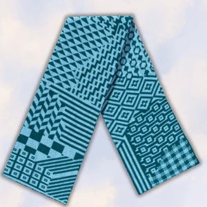May include: A long, rectangular knit scarf featuring a two-tone geometric pattern in teal and light blue. The design consists of various sections including triangles, stripes, squares, and interlocking diamond shapes across the entire fabric surface.