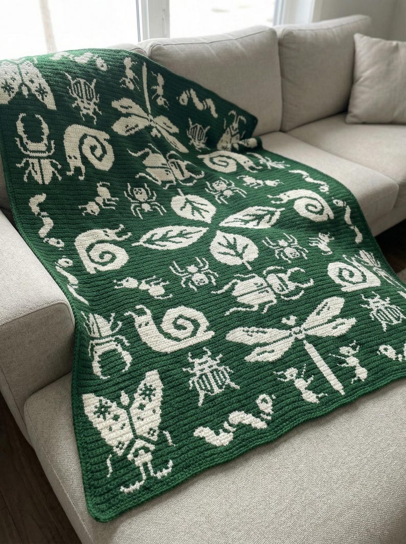 May include: A dark green crochet blanket featuring a repeating cream-colored pattern of various insects, including dragonflies, beetles, snails, and caterpillars, interspersed with leaf motifs across the entire rectangular textile surface.