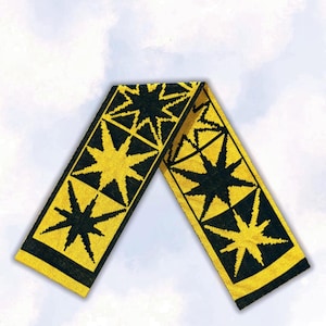 May include: A long, rectangular knit scarf featuring a repeating pattern of large, eight-pointed stars. The design consists of vibrant yellow stars set against a deep black background, with a consistent geometric motif across the entire length.