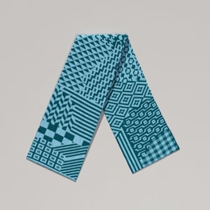 May include: A teal scarf with a geometric pattern. The scarf features various designs, including triangles, diamonds, and stripes. The scarf is made of a soft material and is folded in half.