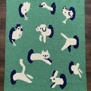 May include: A white ceramic mug with a black handle and the text "But First, Coffee" in a bold, black font. The mug is filled with a dark liquid, likely coffee, and sits on a light-colored surface.