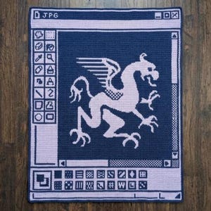 May include: A navy blue and lilac crocheted rug with a griffin design inside a computer interface frame. The rug has the text "JPG" in the top left corner and a series of icons down the left side.