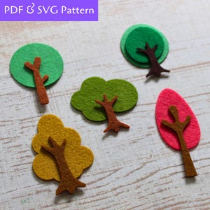 May include: Five felt tree shapes in different colors, including green, yellow, red, and brown. The trees are simple shapes with brown felt trunks.