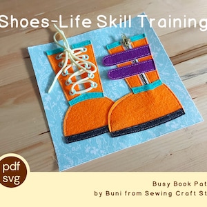 May include: A felt busy book page with two orange boots. One boot has a zipper and the other has laces. The page is on a light blue background with a floral pattern. The text "Shoes-Life Skill Training" is at the top of the page. The text "Busy Book Pattern by Buni from Sewing Craft Studio" is at the bottom of the page.