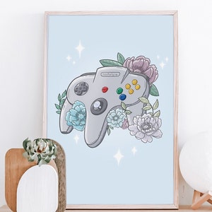 Könnte beinhalten: Ein gerahmter Druck eines grauen Nintendo 64-Controllers mit Blumen und Sternen auf hellblauem Hintergrund.