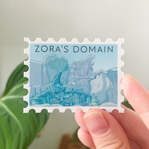 May include: A blue and white sticker with a stylized image of a mountain range and the text "Zora's Domain".