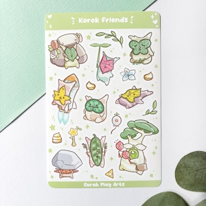 Könnte beinhalten: Ein Stickerbogen mit dem Text "Korok Friends" und Illustrationen verschiedener Korok-Charaktere. Die Aufkleber weisen eine Vielzahl von Farben auf, darunter Grün, Gelb, Rosa und Weiß. Der Name des Künstlers, "Sarah May Arts", ist unten aufgedruckt.