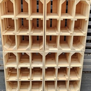 May include: A stack of four wooden crates, each with multiple cubbyhole compartments. The crates are constructed from light-colored, unfinished wood, with visible grain. The design features open fronts and backs, and the crates are arranged in a grid-like pattern.