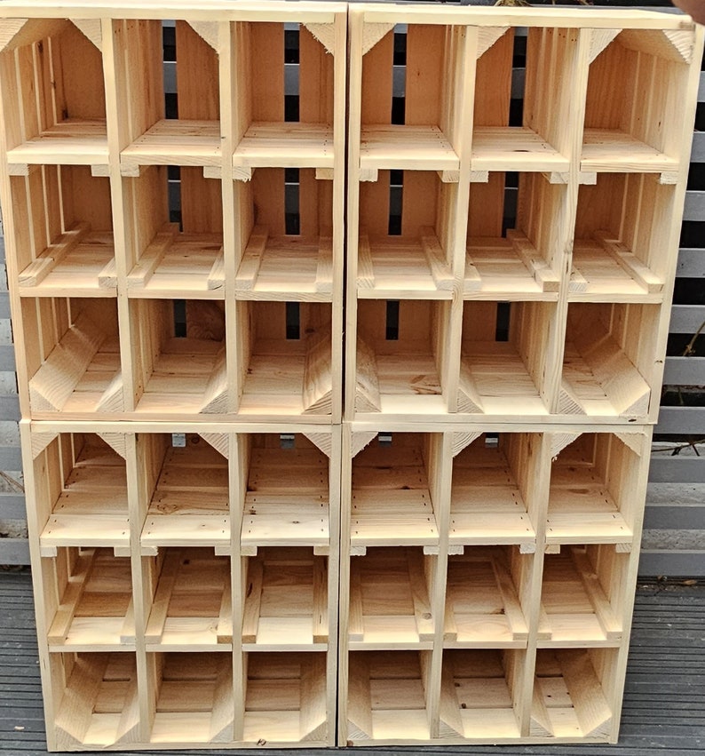 May include: A stack of four wooden crates, each with multiple cubbyhole compartments. The crates are constructed from light-colored, unfinished wood, with visible grain. The design features open fronts and backs, and the crates are arranged in a grid-like pattern.