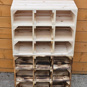May include: A wooden storage shelf with a natural finish, featuring multiple cubby spaces. The top section is unfinished, while the bottom section has a burnt wood appearance. The shelf is constructed from wooden planks and is suitable for organizing items.