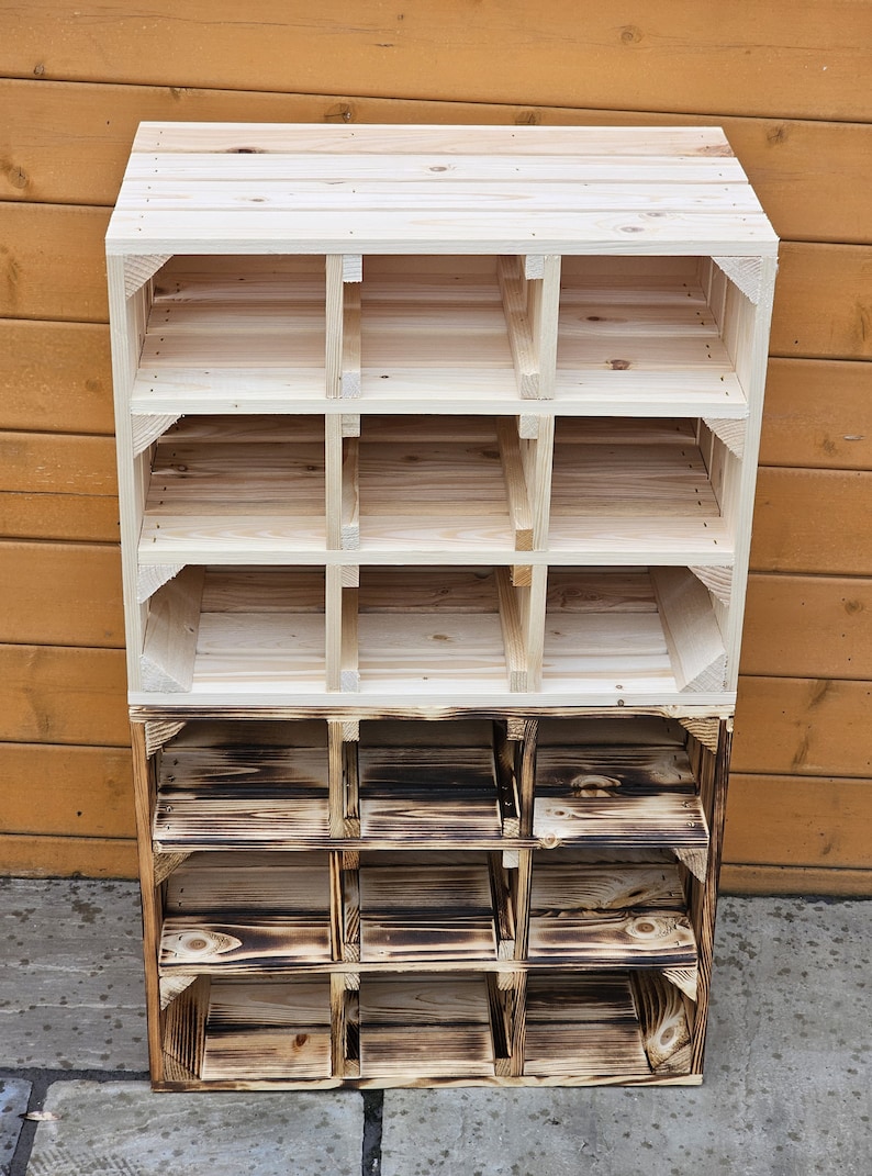May include: A wooden storage shelf with a natural finish, featuring multiple cubby spaces. The top section is unfinished, while the bottom section has a burnt wood appearance. The shelf is constructed from wooden planks and is suitable for organizing items.