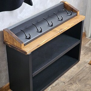 Op de afbeelding: Een zwarte houten kapstok met twee planken en zes metalen haken. De kapstok is gemaakt van gerecycled hout en heeft een rustieke afwerking.