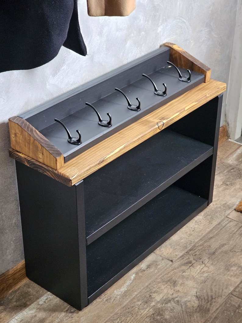 Op de afbeelding: Een zwarte houten kapstok met twee planken en zes metalen haken. De kapstok is gemaakt van gerecycled hout en heeft een rustieke afwerking.