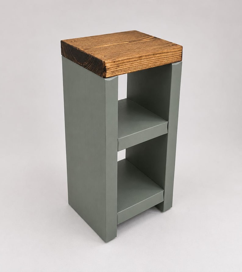 May include: A small, gray wooden side table with two shelves. The top is made of a stained, light brown wood. The table is a simple, modern design, suitable for a living room or bedroom. The table is approximately 28 inches tall.