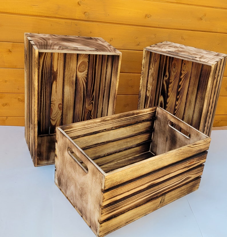 Puede incluir: Tres cajas de madera con un acabado r&uacute;stico quemado. Las cajas est&aacute;n apiladas una encima de la otra, con la caja m&aacute;s grande en la parte inferior y la caja m&aacute;s peque&ntilde;a en la parte superior. Las cajas est&aacute;n hechas de madera natural y tienen un aspecto desgastado.