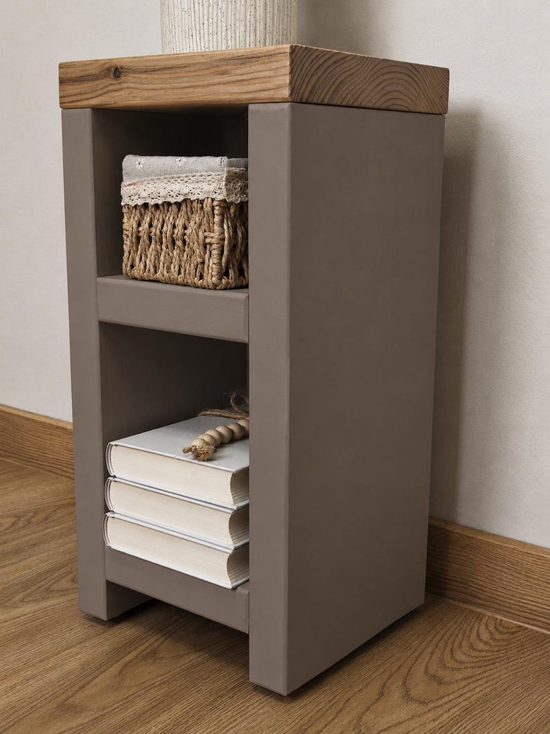 May include: A gray nightstand with a natural wood top. The nightstand has two shelves, one with a woven basket and the other with three books. A decorative item sits on top. The nightstand is on a wooden floor.
