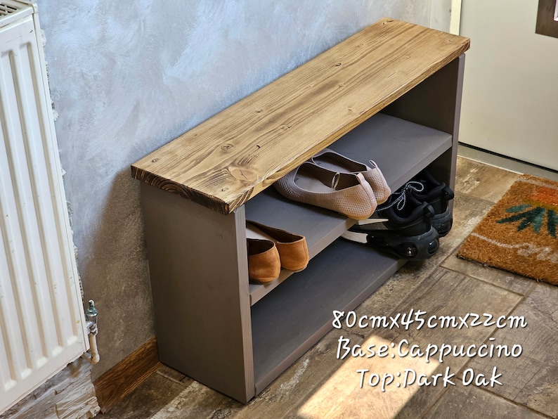 Op de afbeelding: Een houten schoenenbank met twee planken. De bovenkant is donker eiken gebeitst en de basis is cappuccino geverfd. De bank is 80 cm x 45 cm x 22 cm.