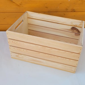 Puede incluir: Una caja de madera natural con forma rectangular y un asa en el lateral. La caja tiene un acabado de madera clara y est&aacute; hecha de madera sin tratar.