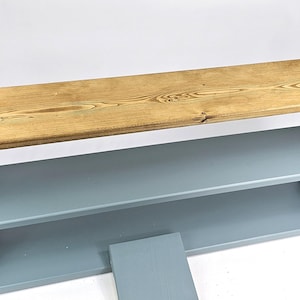May include: A two-shelf bookcase with a light blue finish and a natural wood top. The top shelf is made of reclaimed wood and has a rustic look.