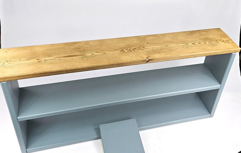 May include: A two-shelf bookcase with a light blue finish and a natural wood top. The top shelf is made of reclaimed wood and has a rustic look.
