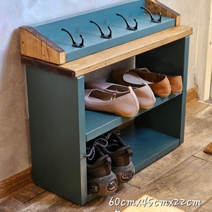Op de afbeelding: Een schoenenrek met twee planken en een bovenste plank met haken. De basis is geverfd in evergreen groen en de bovenkant is donker eiken. Het rek meet 60 cm x 45 cm x 22 cm.