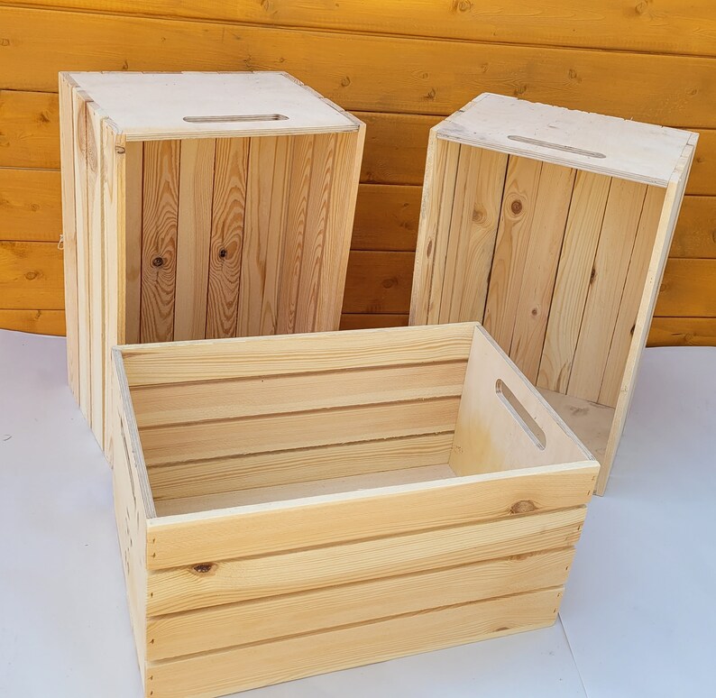 Puede incluir: Tres cajas de madera, dos est&aacute;n apiladas una encima de la otra, la tercera est&aacute; delante de la pila. Las cajas son de madera natural con un acabado marr&oacute;n claro. Las cajas tienen un dise&ntilde;o sencillo con una forma rectangular y un asa en la parte superior.