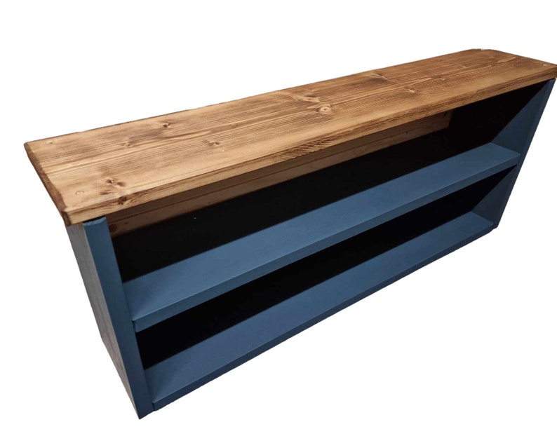 May include: A wooden shelf unit with two shelves painted a dark blue color. The top shelf is made of natural wood and is unfinished. The shelf unit is angled and has a rustic look.