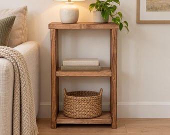 May include: A rectangular wooden console table with a medium brown finish, featuring two open shelves. The top shelf holds two stacked books, while the bottom shelf contains a round, woven seagrass basket with two handles.