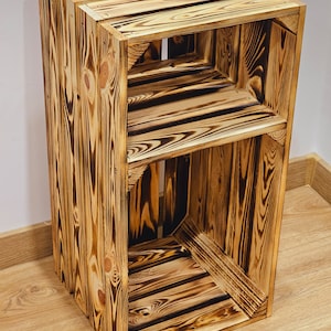 May include: A wooden shelf unit made from reclaimed wood with a rustic, burnt finish. The shelf has two open shelves and is ideal for displaying decorative items or storing small items.